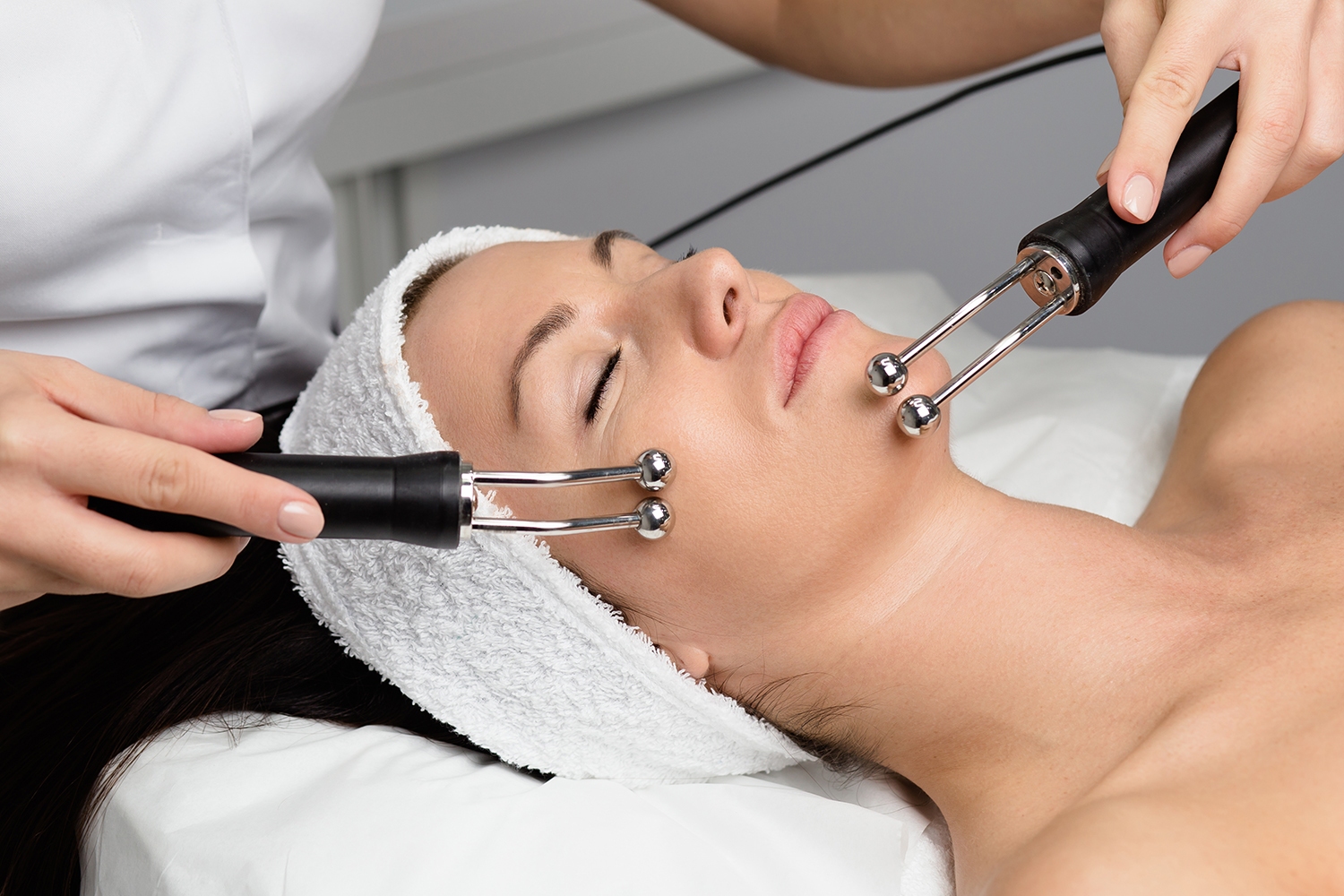 Beautiful woman receiving facial microcurrent treatment at spa salon