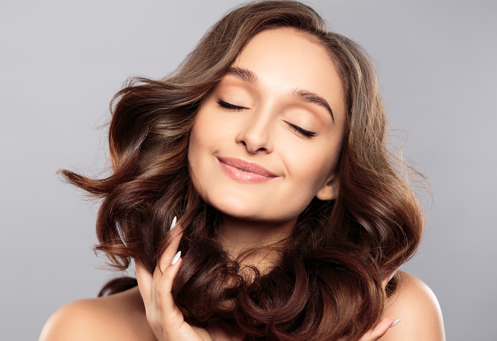 Brunette girl with healthy curly hair and natural make up . Beautiful model woman with wavy hairstyle