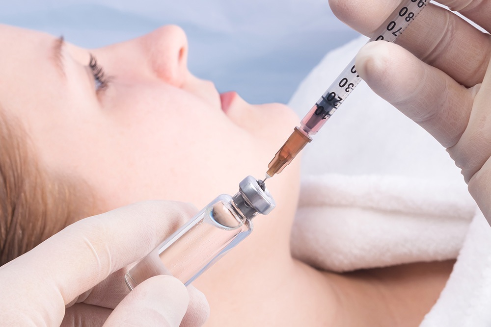 hands in gloves are gaining an injection from a jar into a syrin hands in gloves are gaining an injection from a jar into a syrin